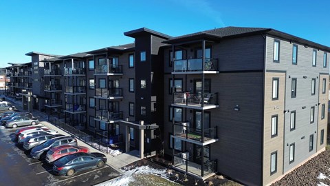 A modern apartment complex with a parking lot in front.