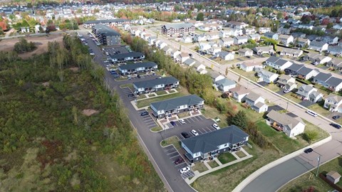 A bird's eye view of a residential area with houses and a parking lot.