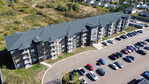 A parking lot with cars and a building with a green roof.
