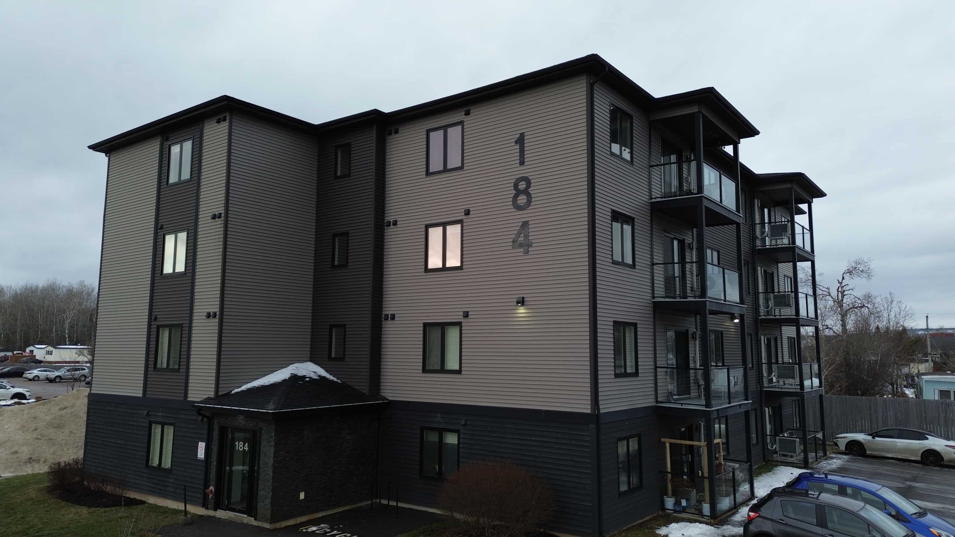 The image shows a modern apartment building with the number 184 on the side.