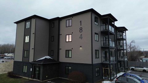 The image shows a modern apartment building with the number 184 on the side.