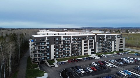 A large apartment complex with a parking lot in front.