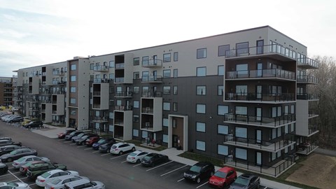A parking lot in front of a multi-story apartment building.
