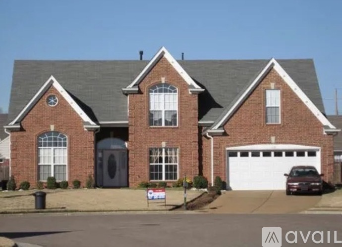 A large brick house with a garage and a car parked in front.