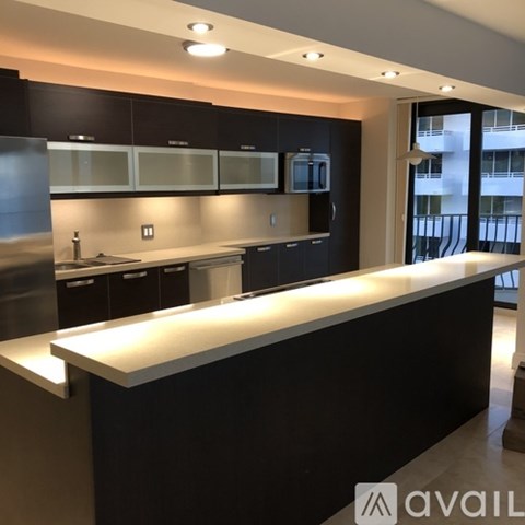A modern kitchen with black cabinets and a long white island.