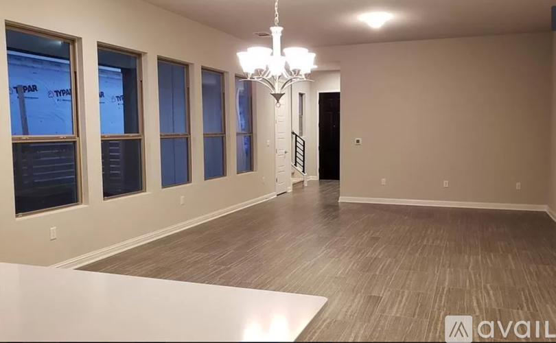 A spacious room with wooden flooring and a chandelier.