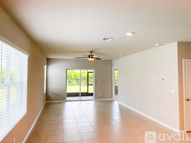 A spacious room with a ceiling fan and sliding glass doors leading to a balcony.
