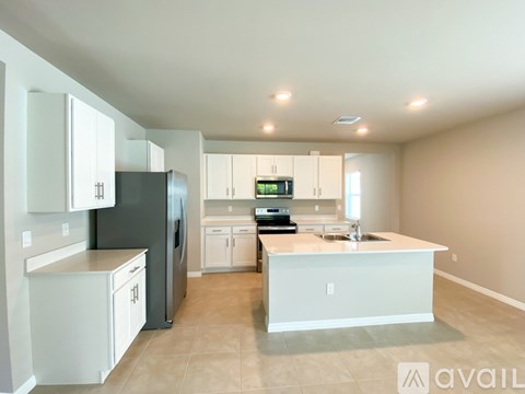 A kitchen with white cabinets and a black refrigerator.
