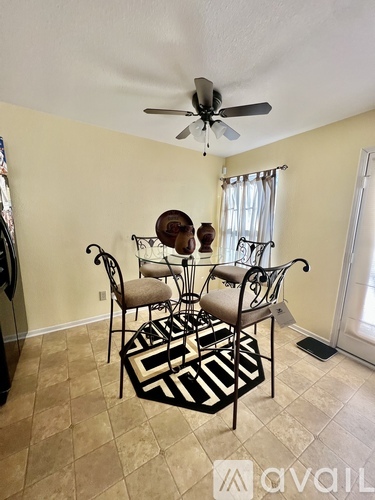 A room with a fan, chairs and a rug.