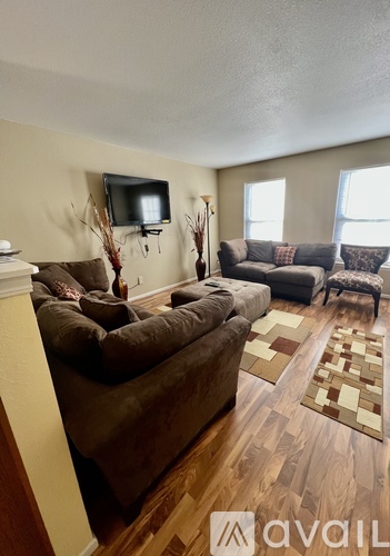 A living room with a brown couch and a television on the wall.