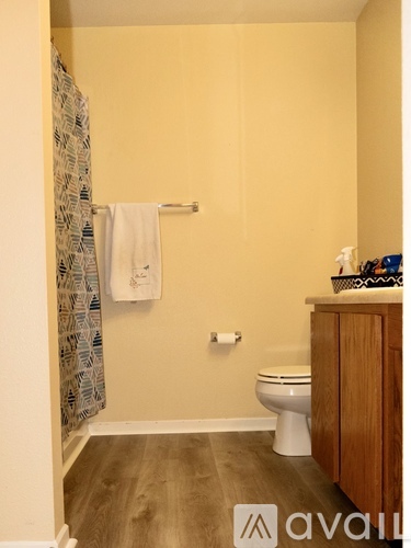 A bathroom with a toilet, a towel, and a shower curtain.