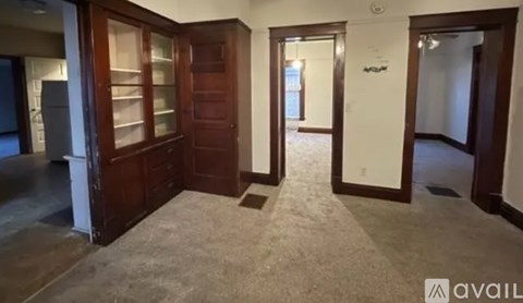 A room with a carpeted floor and a wooden cabinet.