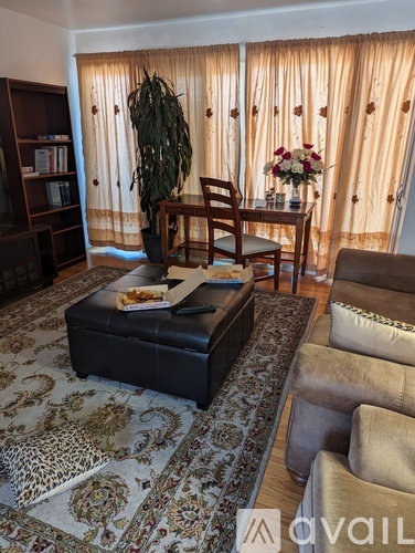 A living room with a leopard print rug and a black ottoman.