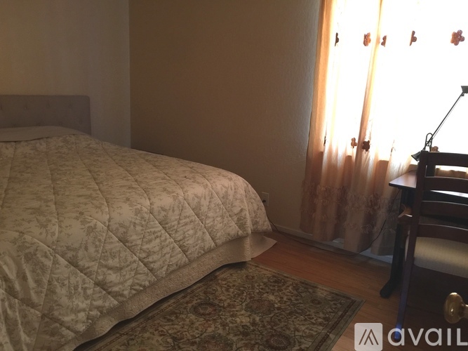 A bedroom with a bed, a chair, and a window with curtains.