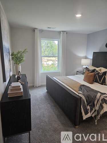 A bedroom with a large bed and a window with curtains.