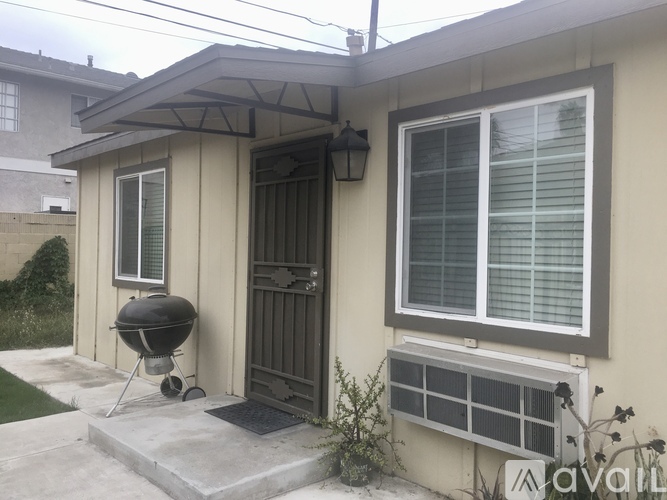 A small house with a grill and air conditioner outside.