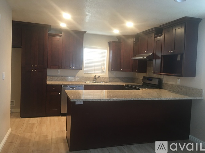 A kitchen with dark wood cabinets and a granite countertop.