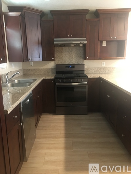 A kitchen with dark wood cabinets and a black stove top oven.