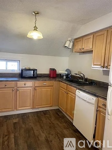 A kitchen with wooden cabinets and a white dishwasher.