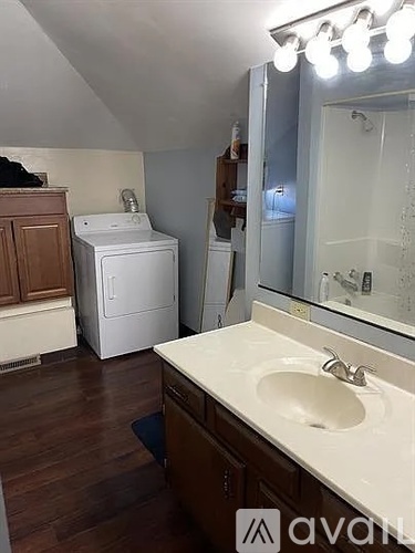 A bathroom with a sink, mirror, and a washing machine.