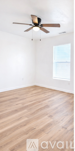 A room with a ceiling fan and wooden flooring.