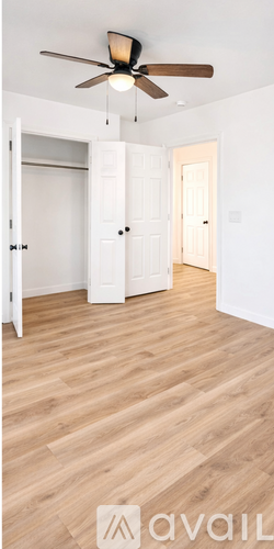 A room with a ceiling fan and wooden flooring.