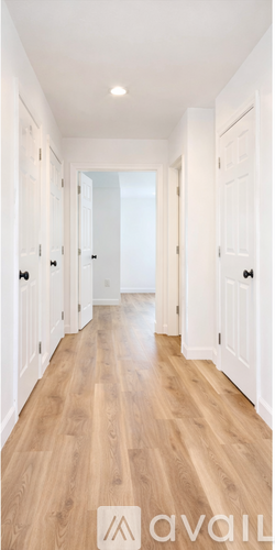 A long hallway with white doors and wooden floors.