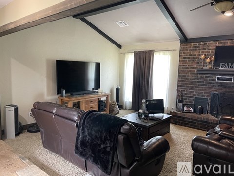 A living room with a brown leather couch and a flat screen TV.