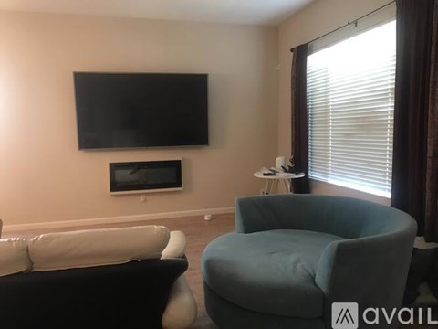 A living room with a black television, a white sofa, and a blue armchair.