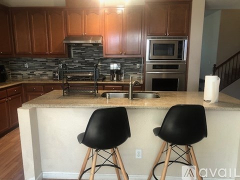 A kitchen with a bar area and two black chairs.