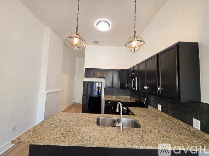A kitchen with granite countertops and black cabinets.