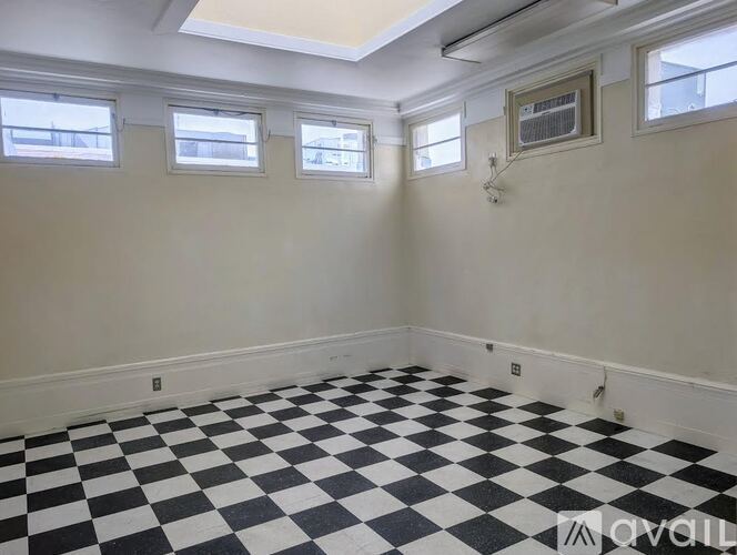 A room with black and white checkered flooring and three windows.