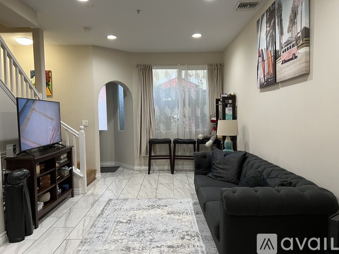 A living room with a black couch, a television, and a rug.