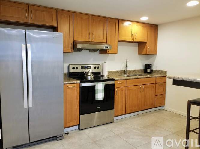 A kitchen with wooden cabinets and a stainless steel refrigerator.