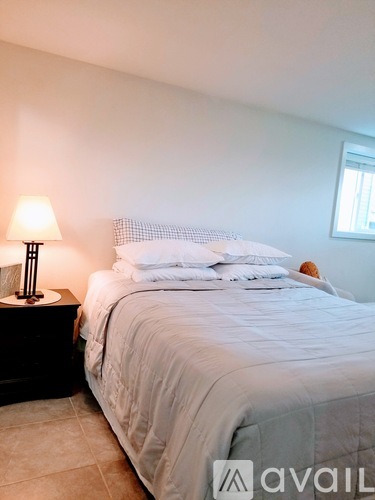 A bedroom with a bed, nightstand, and lamp.