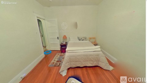 A bedroom with a bed and a rug on the floor.