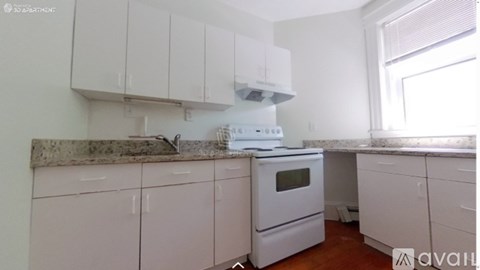 A kitchen with white cabinets and a marble countertop.