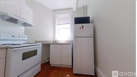 A kitchen with white appliances and wooden floors.