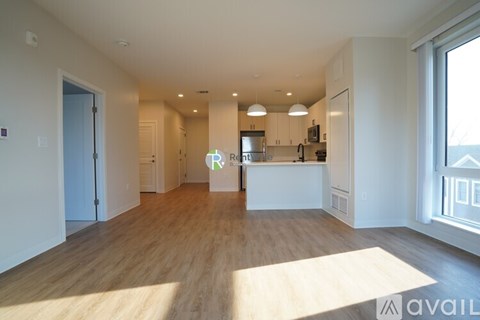 A spacious kitchen with wooden floors and white walls.