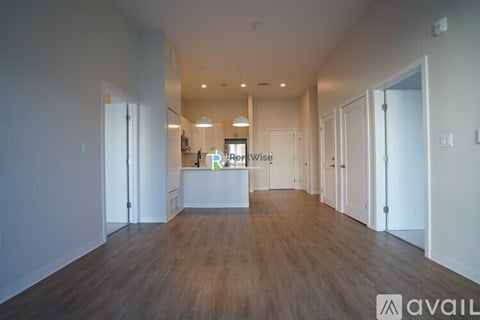 A spacious, empty room with wooden floors and white walls.