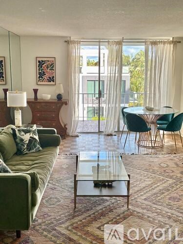 A living room with a green couch and a glass coffee table.
