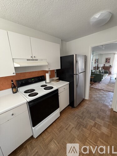 A kitchen with white cabinets and a black fridge.