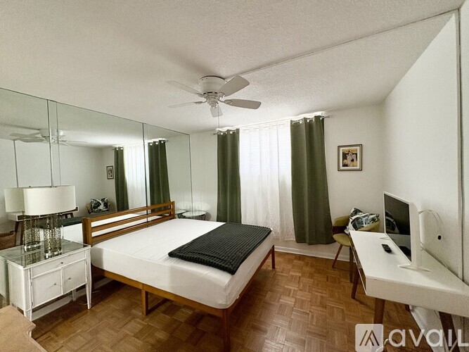 A bedroom with a bed, desk, and mirror.