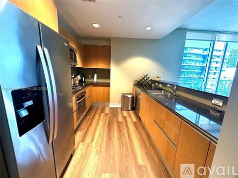 A modern kitchen with wooden floors and stainless steel appliances.