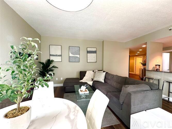 A living room with a grey couch and a green plant.