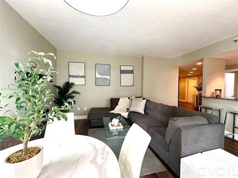 A living room with a grey couch and a green plant.