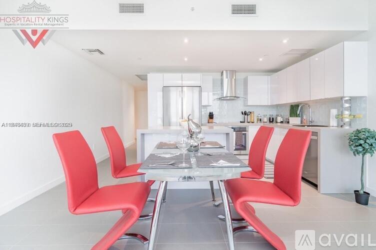 A modern dining room with red chairs and a glass table.