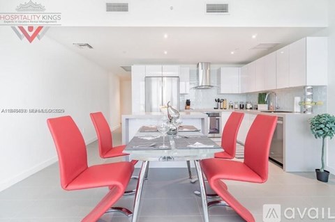 A modern dining room with red chairs and a glass table.