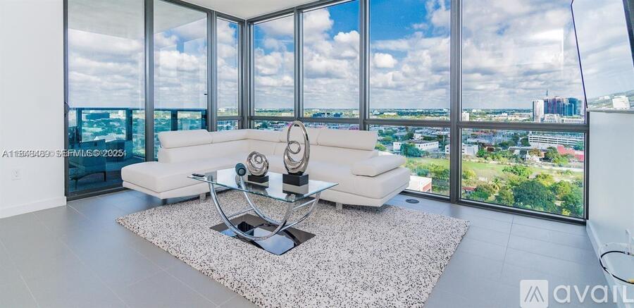 A living room with a white couch and a large window overlooking a cityscape.