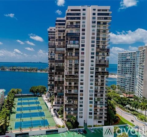 A tall white building with a tennis court in front of it.